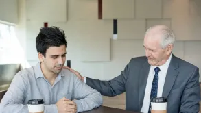 Elderly Man Comforting Young Man