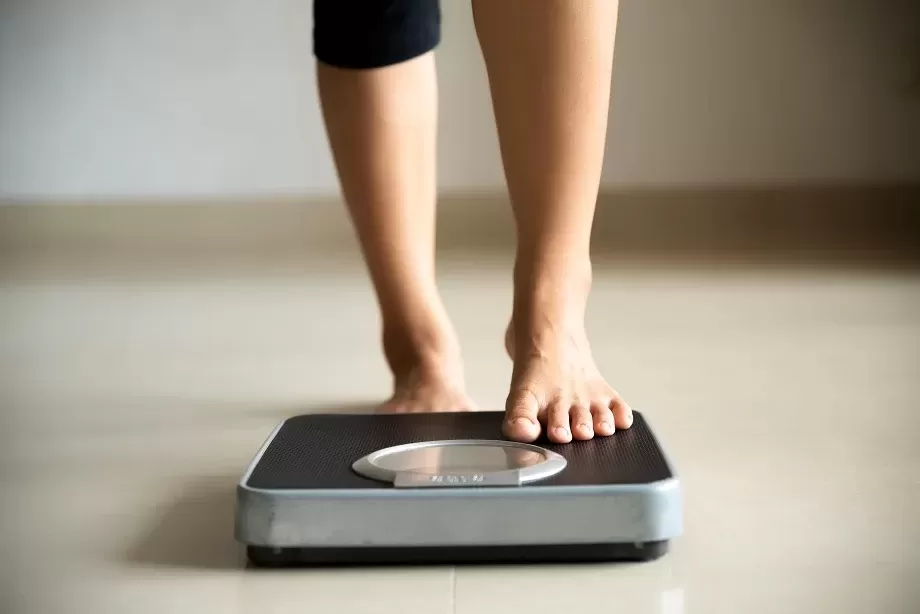 A Person Checking Weight On A Weighing Machine