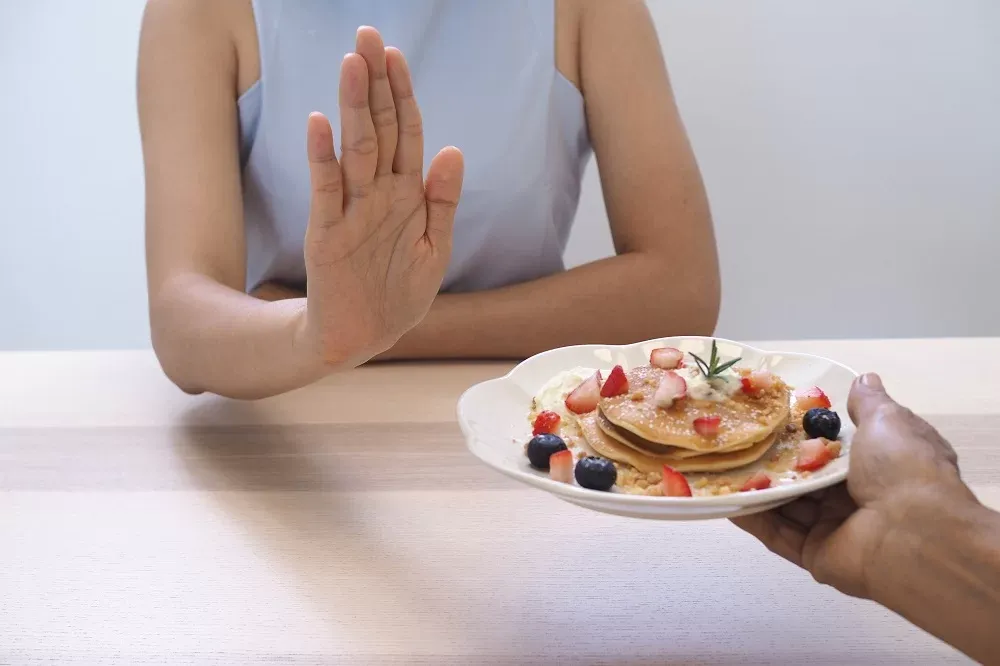 Person Offering A Plate Of Pancakes To A Woman