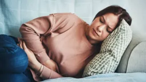 A Woman Lying On A Bed Holding Her Stomach