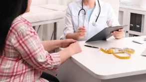 Doctor Talking To Patient With Measuring Tape On Table