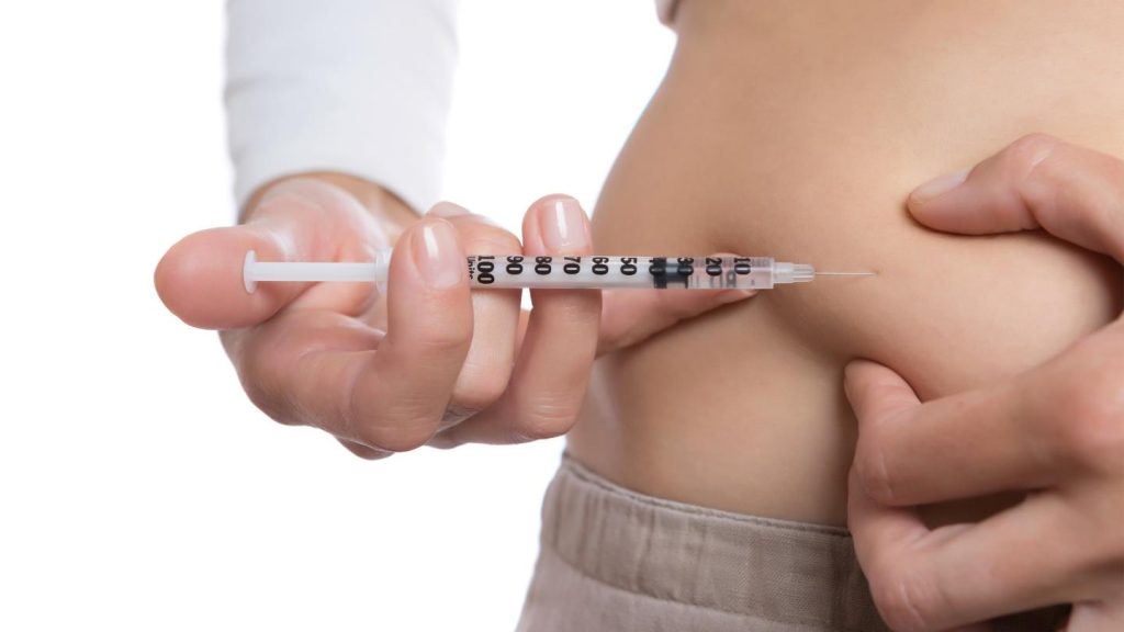 Person Injecting Needle Into Abdomen
